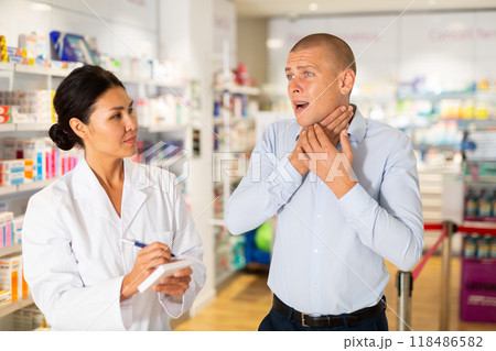 Man complaining to female druggist about sore throat Man complaining to female druggist about sore throat 118486582
