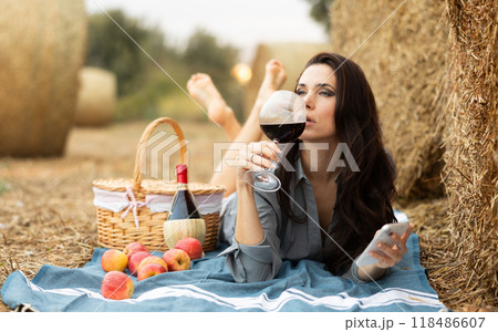 Woman lying with wine and phone during picnic 118486607