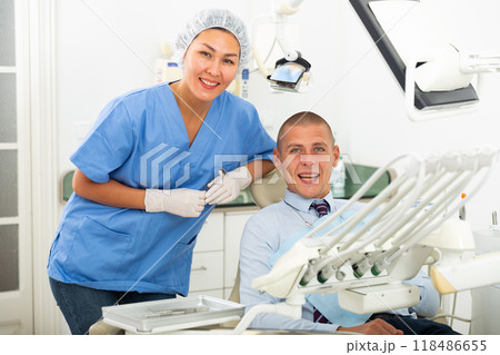 Dentist and happy patient sitting in dental chair 118486655