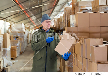 Store worker scans qr code on boxes using smartphone in warehouse shop Store worker scans qr code on boxes using smartphone in warehouse shop 118486756