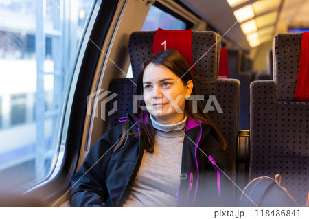 Woman looking at scenery outside window while traveling by train 118486841