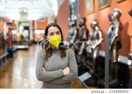Interested brunette in mask visiting exhibition of historical museum Interested brunette in mask visiting exhibition of historical museum 118486892