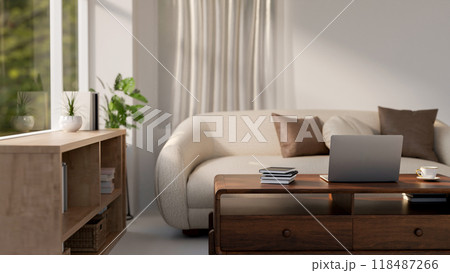 A laptop sits on a hardwood coffee table in a cozy, contemporary living room. 118487266