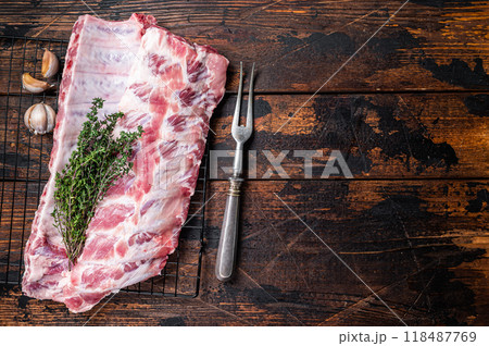 Raw pork spare ribs on a rack with herbs. Wooden background. Top view. Copy space 118487769