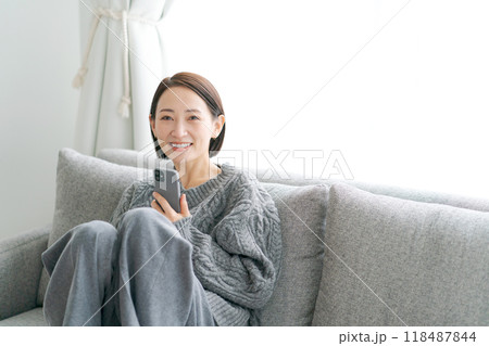 ソファーに座ってスマホを使う女性 118487844