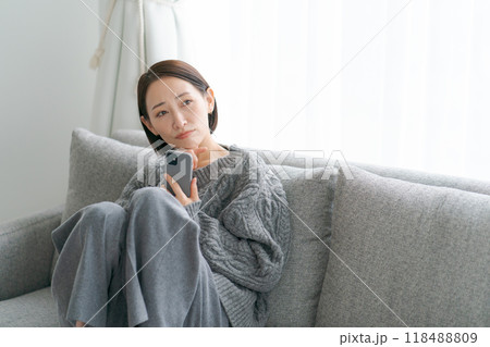 ソファーに座ってスマホを使う女性 118488809