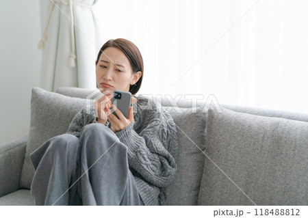 ソファーに座ってスマホを使う女性 ソファーに座ってスマホを使う女性 118488812