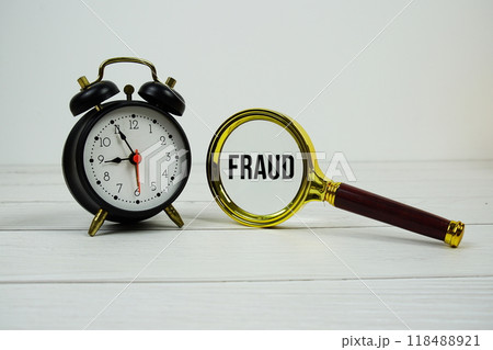Fraud text with magnifying and alarm clock on wooden background Fraud text with magnifying and alarm clock on wooden background 118488921