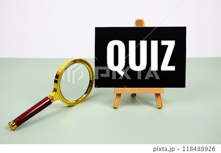 Quiz text on paper card with magnifying glass on green background 118488926