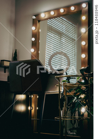 Makeup mirror with bulb lights and blogger circle. Beauty salon interior. Illuminated selfie mirror with leather chair. Luxury barbershop design. Hair salon workplace. Big mirror in beauty studio. 118488946