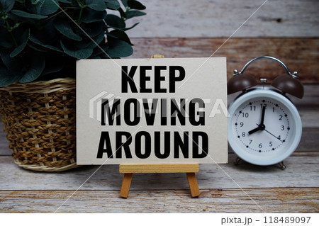 Keep Moving Around text on paper card with alarm clcok on wooden background 118489097