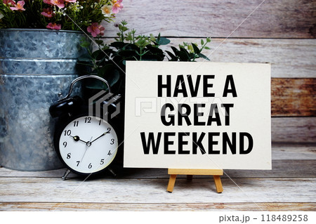 Have a great weekend text on paper card and easel standing with alarm clock on wooden background Have a great weekend text on paper card and easel standing with alarm clock on wooden background 118489258