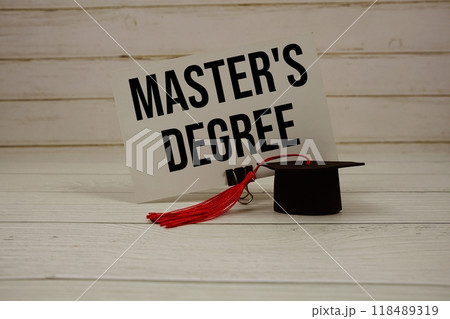 Master's Degree text on paper card with small graduation cap on wooden background 118489319