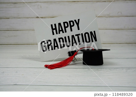 Happy Graduation text on paper card with small graduation cap on wooden background 118489320