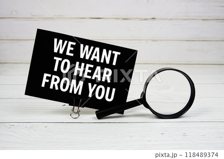 We Want To Hear From You text message on paper card with magnifying glass on wooden background 118489374