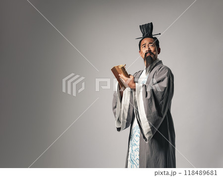 三国志に登場するような中国歴史上の偉人が竹簡に筆で漢文を書くシーン 118489681