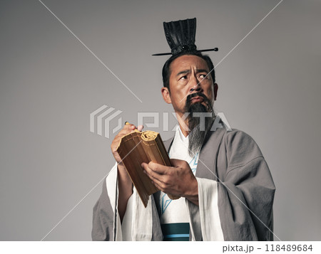 三国志に登場するような中国歴史上の偉人が竹簡に筆で何かを書くシーン 118489684