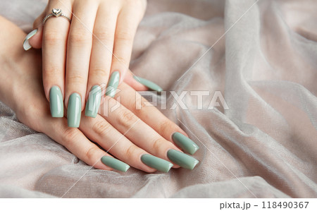 Elegant hands with long green nails resting on soft fabric Elegant hands with long green nails resting on soft fabric 118490367