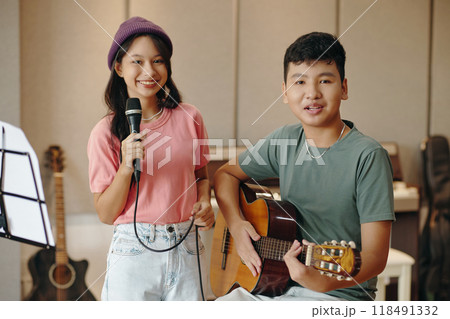 Smiling Teenagers Performing and Playing Guitar in Room 118491332