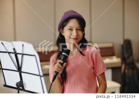 Portrait of Smiling Young Woman Holding Microphone in Studio Portrait of Smiling Young Woman Holding Microphone in Studio 118491334