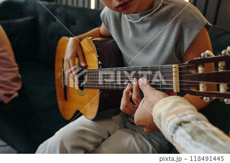 Playing Acoustic Guitar While Relaxing on Sofa 118491445