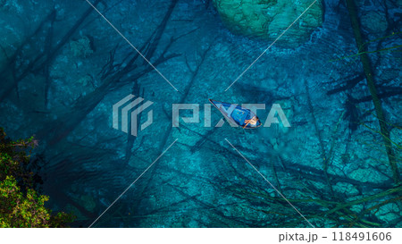 Woman on boat float in most transparent lake with crystal blue fresh water in Sulawesi, Indonesia. Aerial view Woman on boat float in most transparent lake with crystal blue fresh water in Sulawesi, Indonesia. Aerial view 118491606