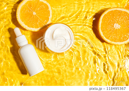 Cosmetic cream and serum bottle in yellow water background with orange citrus 118495367