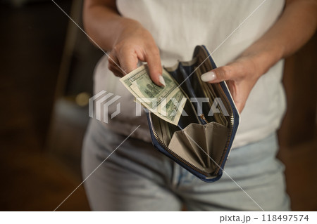 Woman opening wallet and taking out banknotes 118497574