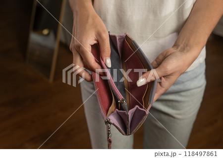 Woman revealing an empty blue wallet, showcasing financial struggles Woman revealing an empty blue wallet, showcasing financial struggles 118497861