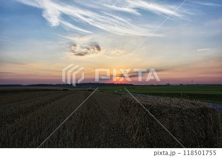 Landscape. The sun sets behind the feathery clouds. Evening sunset in the field after harvesting 118501755