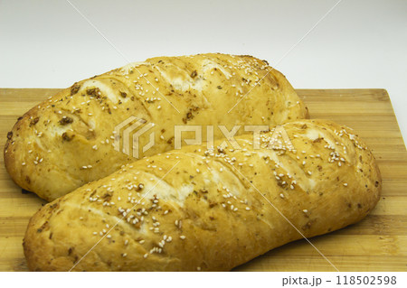 Wheat bread baked from flour at home. Tasty bread on wooden board against background. Food with NO GMO. Homemade bread with spice on it. Wheat bread baked from flour at home. Tasty bread on wooden board against background. Food with NO GMO. Homemade bread with spice on it. 118502598