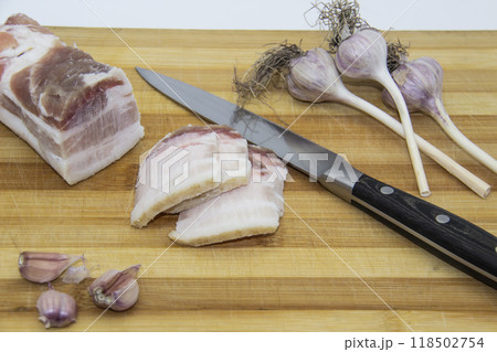 Ukrainian products raw lard with peppercorn and garlic, knife, slices of salo being on cutting board. Ukrainian traditional food concept. Ukrainian products raw lard with peppercorn and garlic, knife, slices of salo being on cutting board. Ukrainian traditional food concept. 118502754