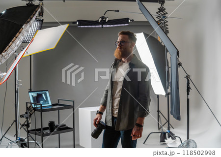 Professional photographer in modern studio with equipment setup and soft lighting 118502998