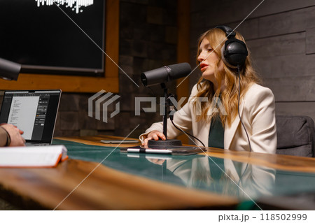 Podcaster recording with headphones and microphone in studio, chatting and broadcasting 118502999