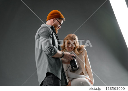 The photographer is displaying the camera screen to a joyful model in a photoshoot session 118503000