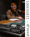 A podcaster is in a studio with recording equipment and microphones, ready to create content 118503001