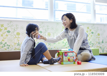 託児所でおもちゃで子供と遊ぶ保育士の女性 118503009