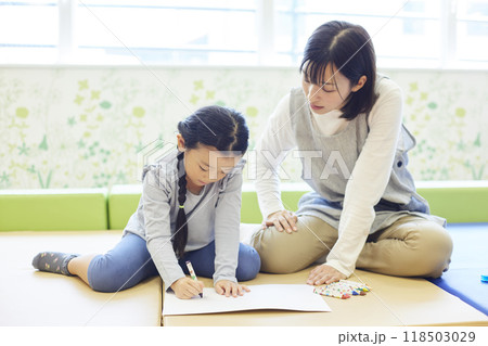 保育園で園児と一緒にお絵描きをする女性保育士 保育園で園児と一緒にお絵描きをする女性保育士 118503029