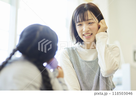 保育室で園児の話に耳を傾ける笑顔の女性保育士 保育室で園児の話に耳を傾ける笑顔の女性保育士 118503046