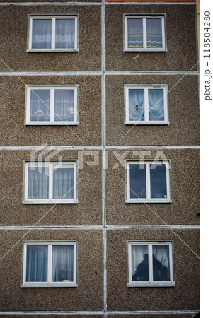 Facade of an apartment building showing multiple windows with curtains and plants Facade of an apartment building showing multiple windows with curtains and plants 118504280