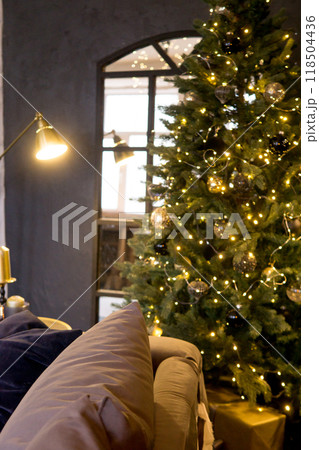 Christmas interior with a beautiful Christmas tree, sofa, light bulbs and dark background. Christmas interior with a beautiful Christmas tree, sofa, light bulbs and dark background. 118504436