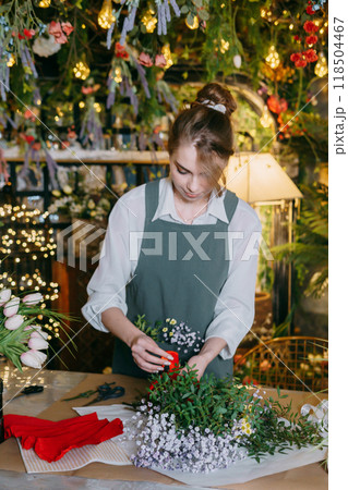 A woman in her florist shop collects bouquets of flowers. The concept of a small business. Bouquets of tulips for the holiday on March 8. 118504467