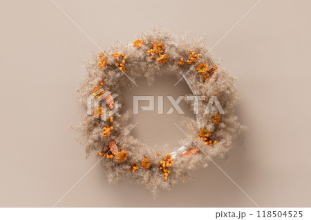 Wreath for Thanksgiving Day with orange flowers and dry natural materials on beige background. Top view. Greeting card with copy space. 118504525