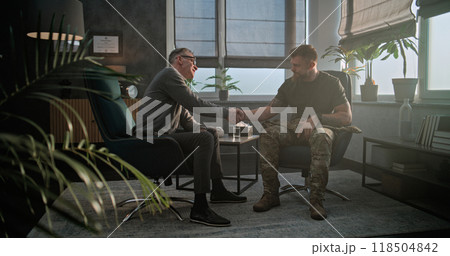 Senior psychologist says goodbye to soldier and looks at camera while sitting in chair 118504842