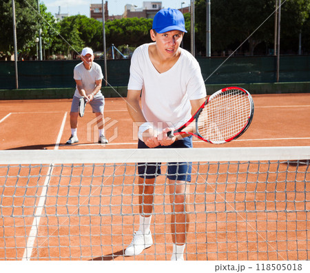 Grandfather and grandson playing tennis court 118505018