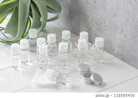 白いタイルの上に配置した化粧品サンプルのミニボトルと観葉植物 118505450