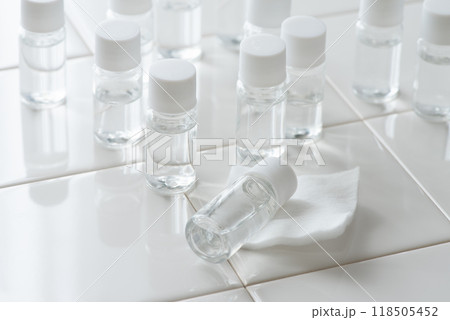 白いタイルの上に並べた化粧水など透明な液体の入った小さなプラスチックボトル 白いタイルの上に並べた化粧水など透明な液体の入った小さなプラスチックボトル 118505452