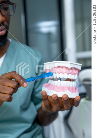 Male doctor providing dental care on model in the clinic, treating caries 118506183