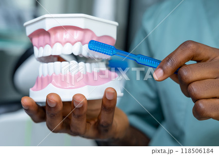 Orthodontist conducting dental cleaning using brush to remove plaque and whiten teeth 118506184