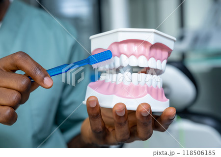 Male doctor providing dental care on model in the clinic, treating caries 118506185